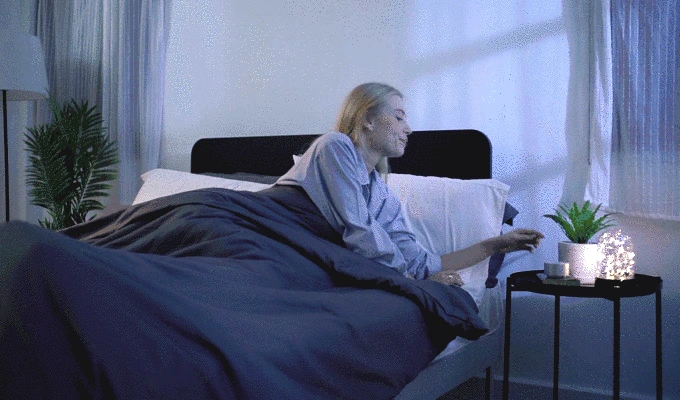 A woman presses Banala Lite at her bedside and settles into bed.